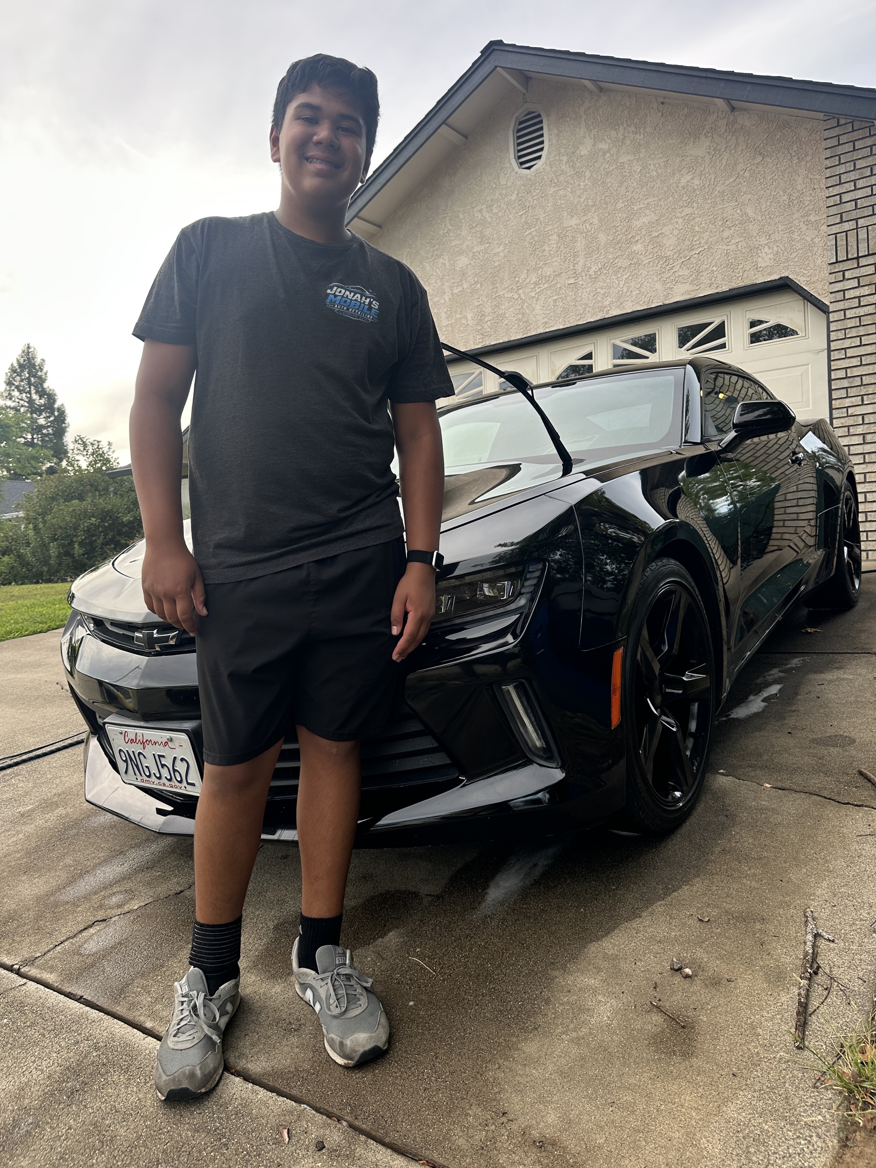 Jonah, founder of Jonah’s Mobile Detailing, standing beside a freshly detailed black Chevrolet Camaro